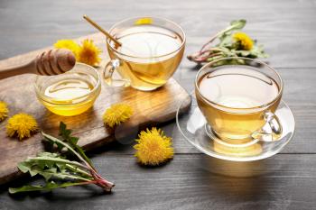 Cups of healthy dandelion tea with honey on table�