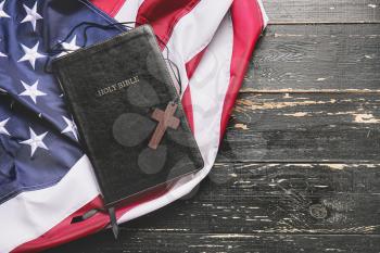 Holy Bible, cross and USA flag on wooden background�
