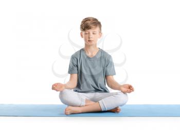 Cute little boy practicing yoga on white background�