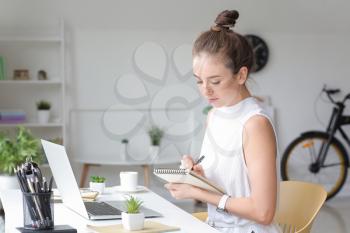Young woman with laptop working at home�