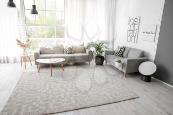 Stylish interior of living room with carpet and sofas�