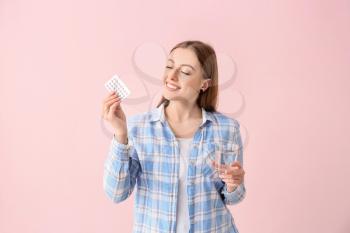 Young woman with birth control pills on color background�