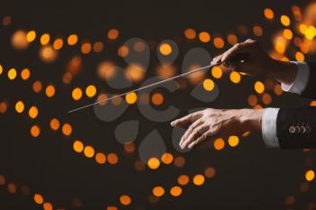 Hands of male conductor on dark background with defocused lights�