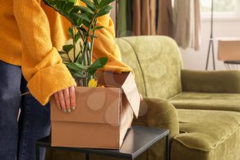 Woman with houseplant in cardboard box on moving day�