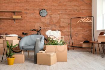 Cardboard boxes with belongings and armchair in new flat on moving day�
