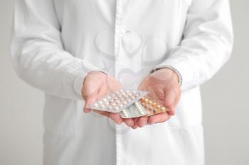 Female gynecologist with birth control pills on grey background, closeup 