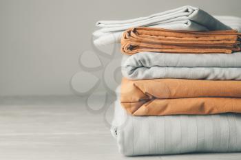 Stack of clean bed sheets on table�