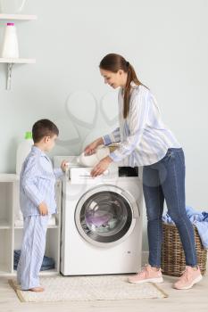 Young woman with her little son doing laundry at home�