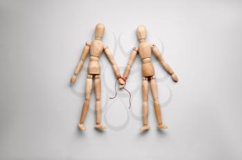 Wooden human figures holding hands on light background. Unity concept�