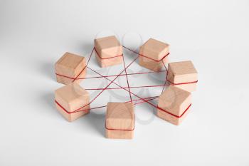 Wooden cubes tied with red thread on light background. Unity concept�
