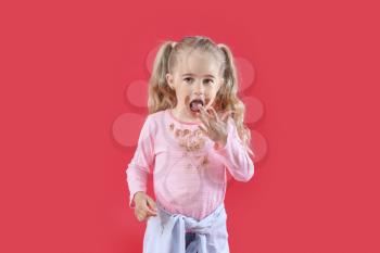 Little girl with chocolate stains on her clothes against color background�