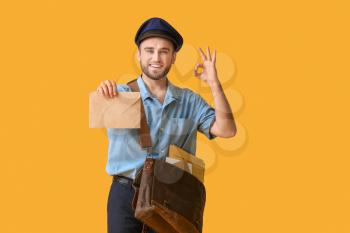 Handsome young postman on color background�