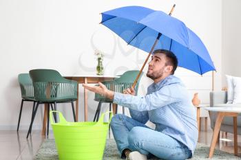 Young man with umbrella suffering from neighbor's flood at home�