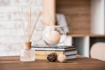 Reed diffuser, books and candle on table in room�