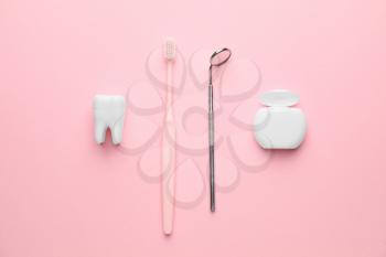 Dental mirror with toothbrush and floss on color background�