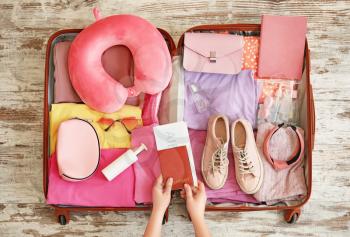 Woman packing suitcase for journey at home, top view�