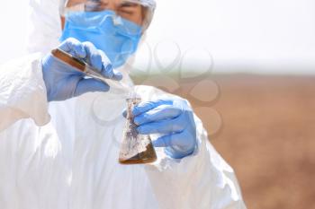 Scientist studying samples of soil in field�