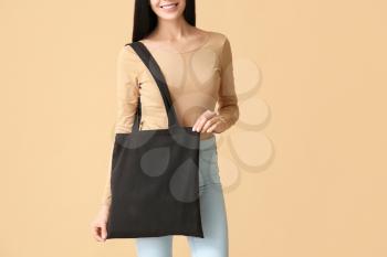 Young woman with eco bag on color background�