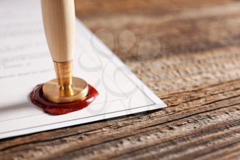 Document with notary public wax seal on table, closeup�