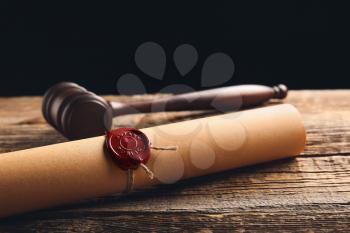 Scroll with notary public wax seal and gavel on table�