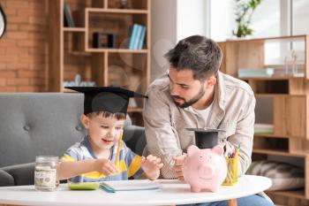 Little boy and father with savings for education at home�