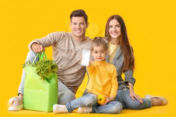Family with food in bag and mobile phone on color background�