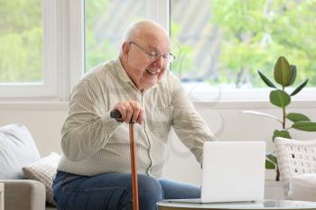 Senior man with laptop at home�