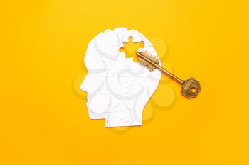 Human head made of puzzle pieces and key on color background�