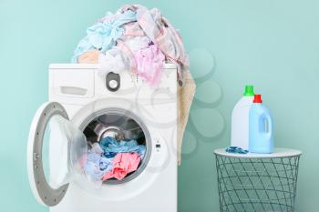 Washing machine with dirty clothes and detergents in home laundry room�