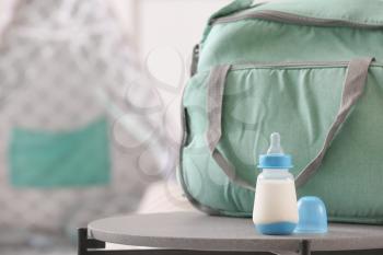 Bottle of milk for baby with bag on table in room�