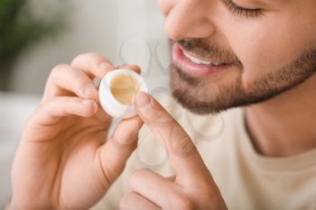 Handsome young man with lip balm at home, closeup�