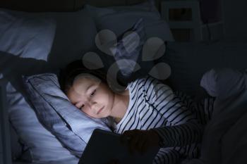Little girl suffering from sleep disorder with tablet computer in bedroom�