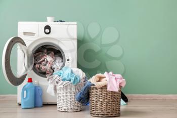 Washing machine with dirty clothes near color wall�