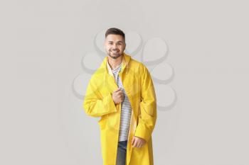 Young man in raincoat on light background�