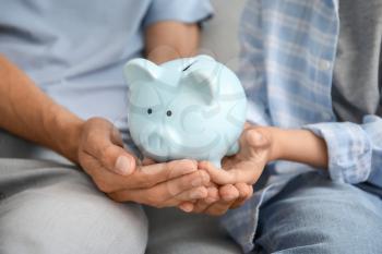 Family with piggy bank at home, closeup�
