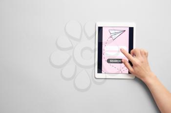 Hand with tablet computer on light background. Concept of online booking�