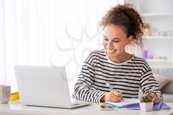 Young woman using laptop for online learning at home�