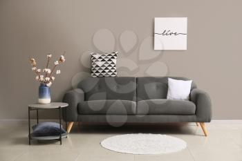 Comfortable sofa near grey wall in room�
