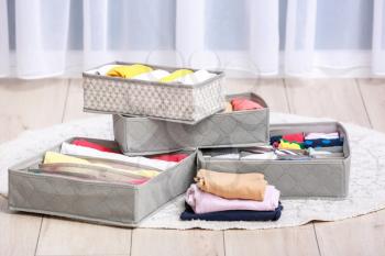 Organizers with clean clothes on wooden floor�