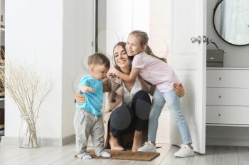 Happy children meeting their mother after work at home�