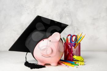 Piggy bank, graduation hat and stationery on table. Tuition fees concept�