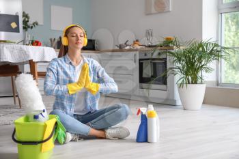 Beautiful young woman meditating during cleaning of kitchen�