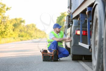 Male driver fixing big truck outdoors�