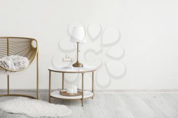 Stylish armchair and table near light wall�