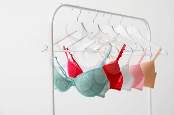 Clothes rack with stylish bras on light background�