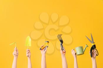 Female hands with gardening tools on color background�
