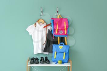 Stylish school uniform with backpacks near color wall�