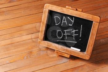 Chalkboard with text DAY OFF on wooden background�