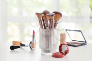 Set of makeup brushes with decorative cosmetics on table�