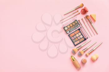 Set of makeup brushes with decorative cosmetics on color background�